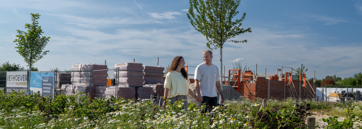 Een jong stel loopt over de bouwplaats van hun nieuwe woning