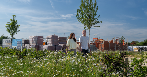 Een jong stel loopt over de bouwplaats van hun nieuwe woning