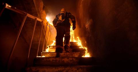 Brandweerman loopt een trap op in een gebouw waar brand is